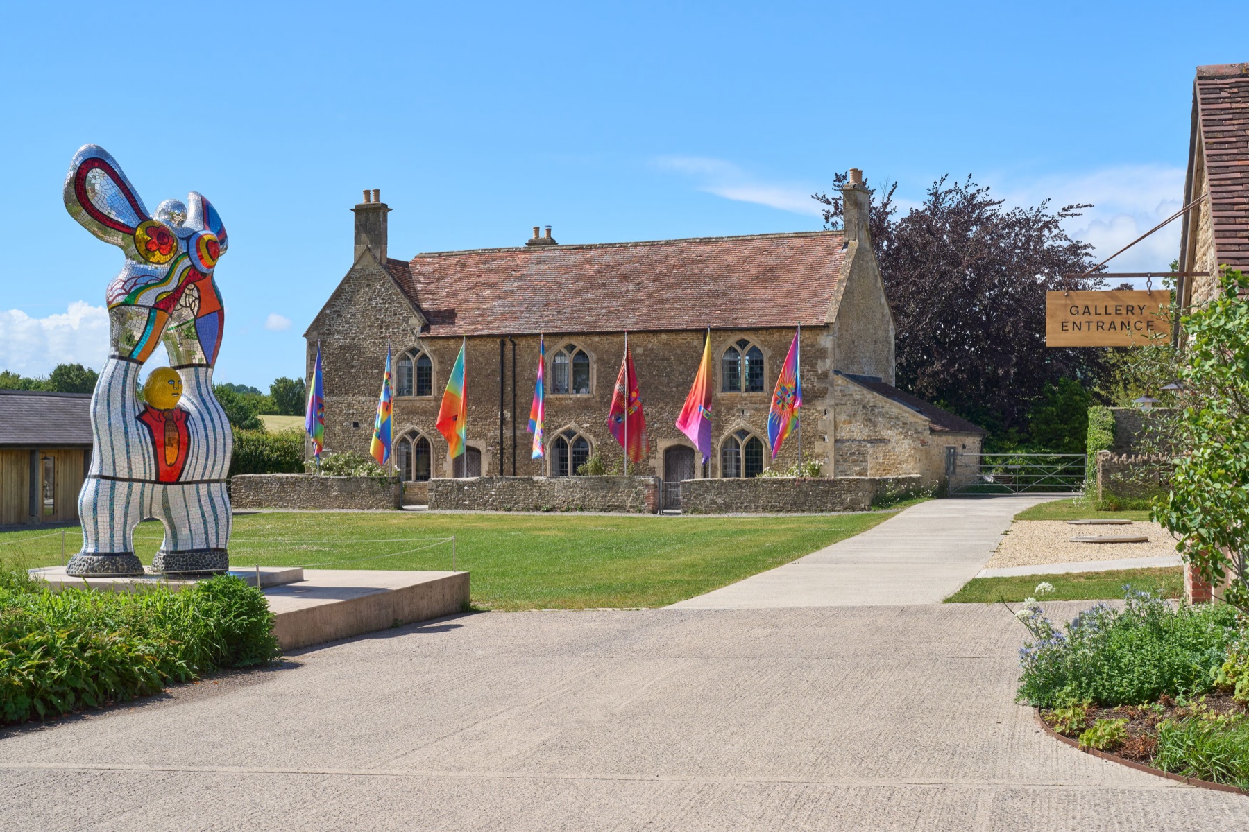 Sculpture and Jeffrey Gibson's colourful flags on the lawn outside the gallery at Hauser & Wirth Somerset